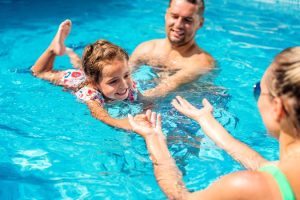 parents-teaching-their-daughter-swimming-pool